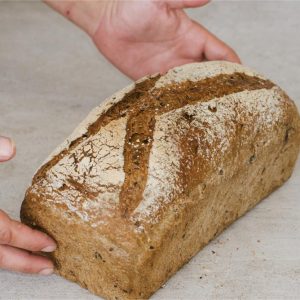 Pan de trigo molido a la piedra y centeno integral con semillas tostadas y malteadas y granos cocidos .